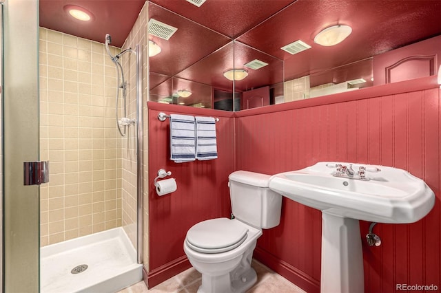 bathroom featuring tile patterned flooring, a shower with shower door, and toilet