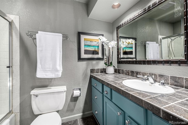 full bathroom with vanity, bath / shower combo with glass door, and toilet