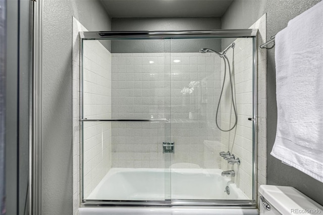 bathroom featuring enclosed tub / shower combo and toilet