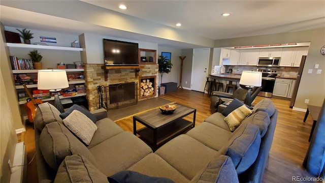 living room with a stone fireplace, sink, and light wood-type flooring