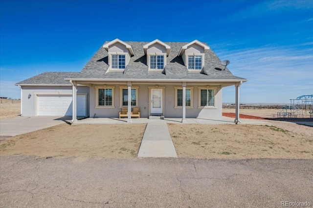 view of front facade with stucco siding, an attached garage, driveway, and a shingled roof