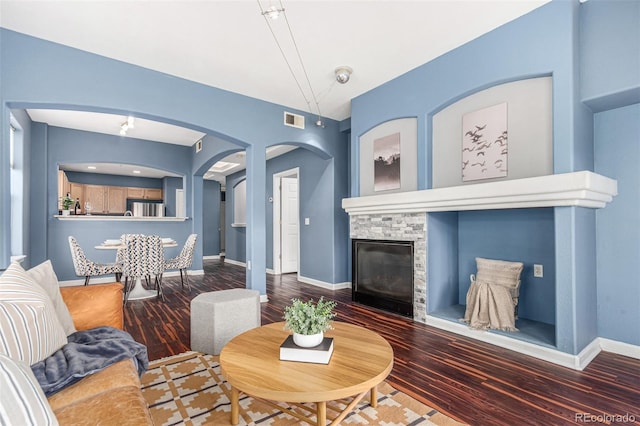 living room featuring wood-type flooring and a stone fireplace