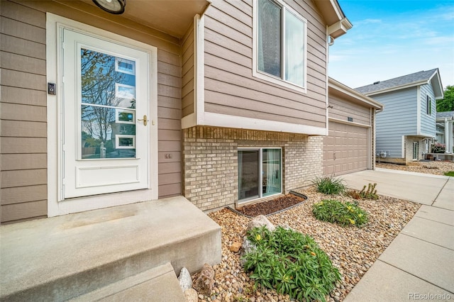1482 S Pitkin Cir, Aurora, CO 80017 - view of exterior entry featuring brick siding, a garage, and concrete driveway