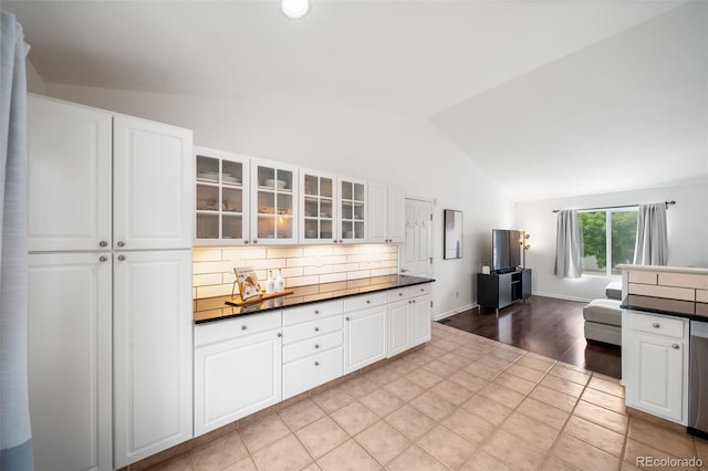 1482 S Pitkin Cir, Aurora, CO 80017 - kitchen featuring dark countertops, lofted ceiling, glass insert cabinets, white cabinets, and backsplash