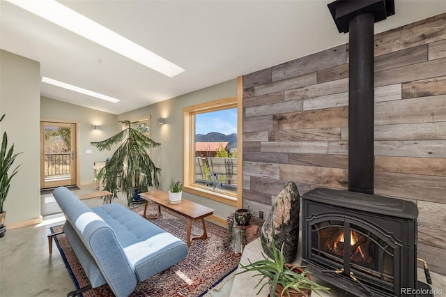 551 Spade Pl, Jefferson, CO 80456 - living area featuring wood walls, lofted ceiling, plenty of natural light, a wood stove, and concrete flooring