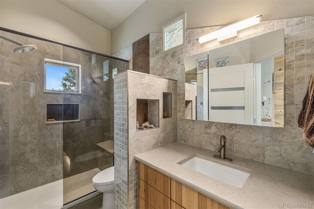 551 Spade Pl, Jefferson, CO 80456 - bathroom featuring tiled shower, toilet, vanity, backsplash, and vaulted ceiling
