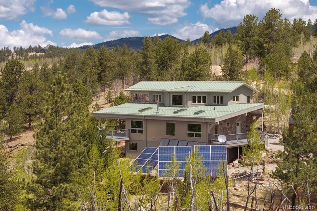 551 Spade Pl, Jefferson, CO 80456 - back of house featuring a wooded view, solar panels, metal roof, a standing seam roof, and stucco siding