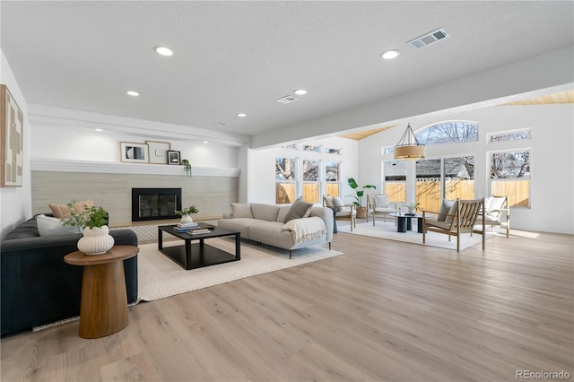 living room with a textured ceiling, a fireplace, and light hardwood / wood-style floors