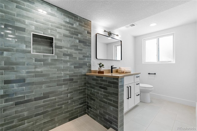 bathroom with tile patterned flooring, vanity, a textured ceiling, and toilet