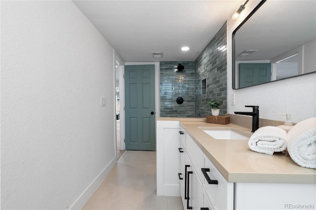 bathroom featuring vanity, tiled shower, and a textured ceiling