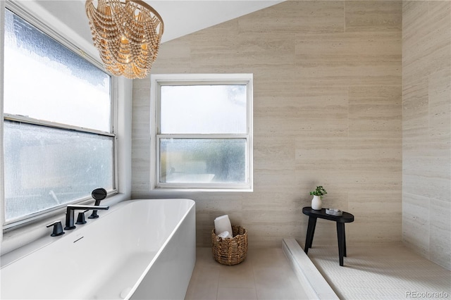 bathroom with lofted ceiling, sink, a notable chandelier, a bath, and tile patterned floors