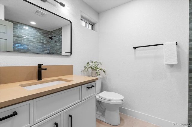 bathroom featuring tile patterned flooring, vanity, a tile shower, and toilet