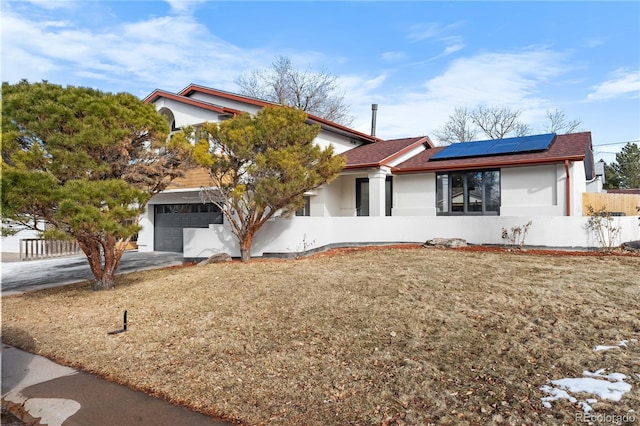 view of front of house with a garage, a front yard, and solar panels