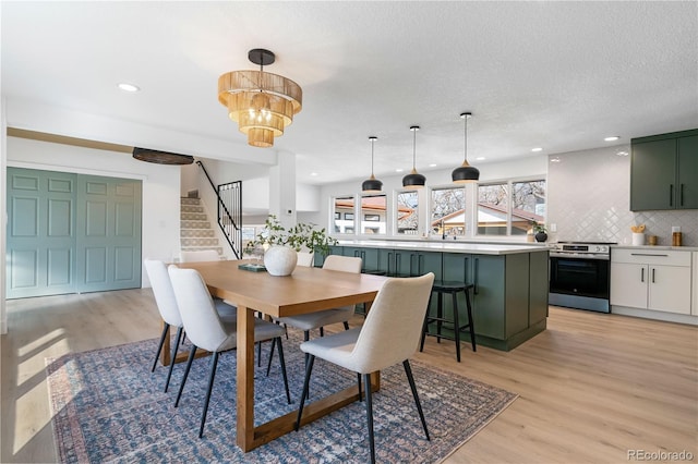 dining room with a chandelier, light hardwood / wood-style flooring, and a textured ceiling