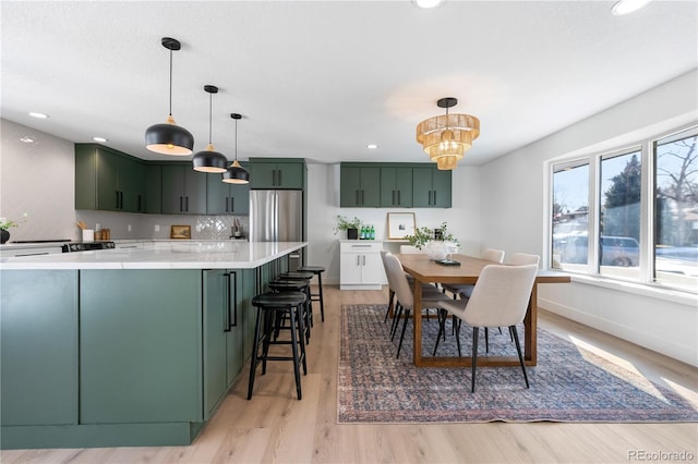 kitchen with light wood-type flooring, pendant lighting, backsplash, and a kitchen breakfast bar