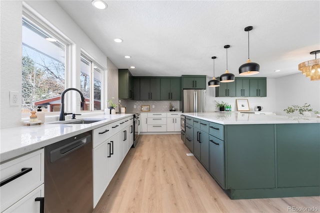 kitchen with sink, hanging light fixtures, stainless steel refrigerator, dishwashing machine, and white cabinets