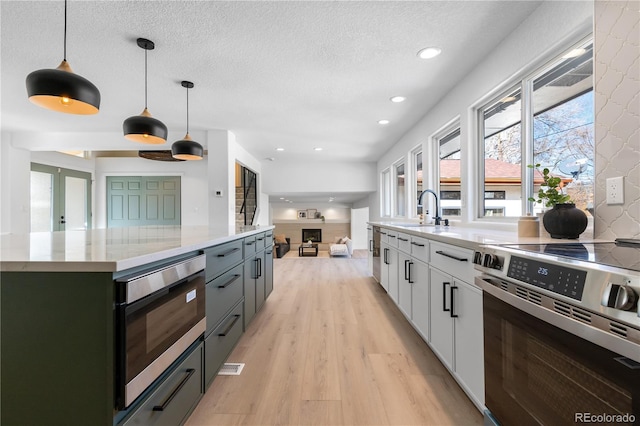 kitchen with sink, white cabinetry, a center island, appliances with stainless steel finishes, and pendant lighting