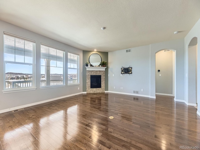 unfurnished living room with a textured ceiling and dark hardwood / wood-style floors