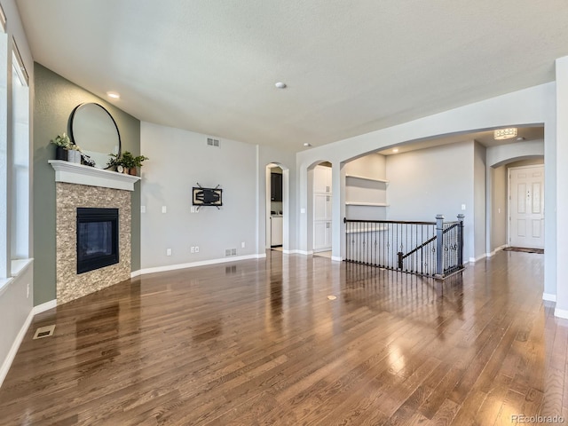 unfurnished living room featuring a textured ceiling, a fireplace, and dark hardwood / wood-style floors