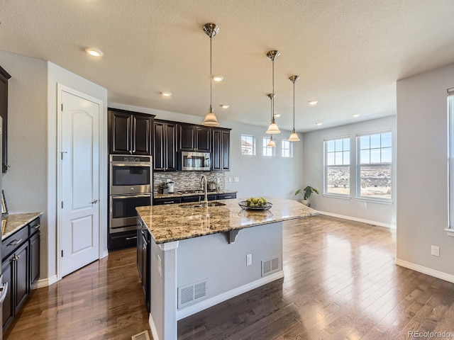 kitchen featuring a center island with sink, pendant lighting, sink, and stainless steel appliances