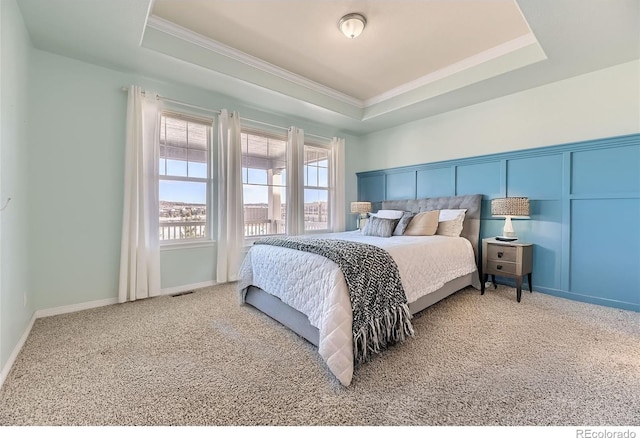 carpeted bedroom with a raised ceiling and crown molding