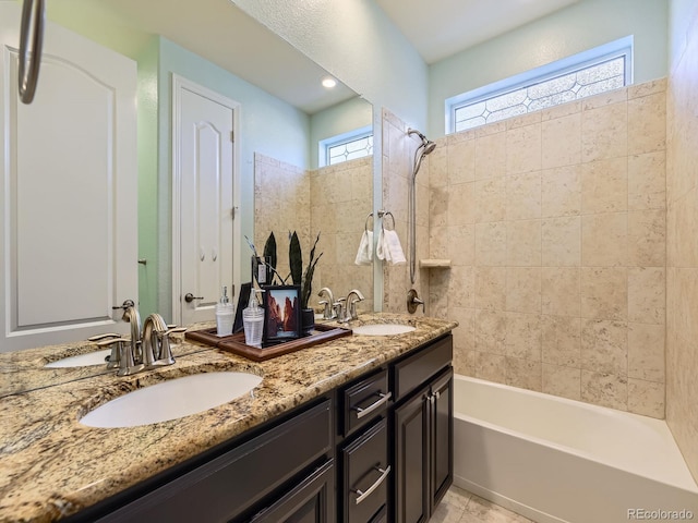 bathroom with tile patterned flooring, vanity, a healthy amount of sunlight, and tiled shower / bath