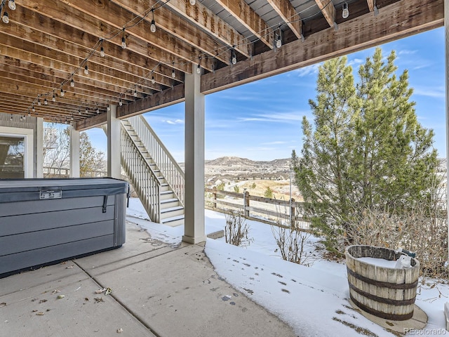 snow covered patio featuring a mountain view and a hot tub