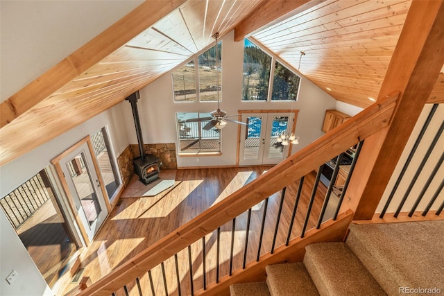 staircase featuring hardwood / wood-style floors, a wood stove, wood ceiling, beam ceiling, and french doors