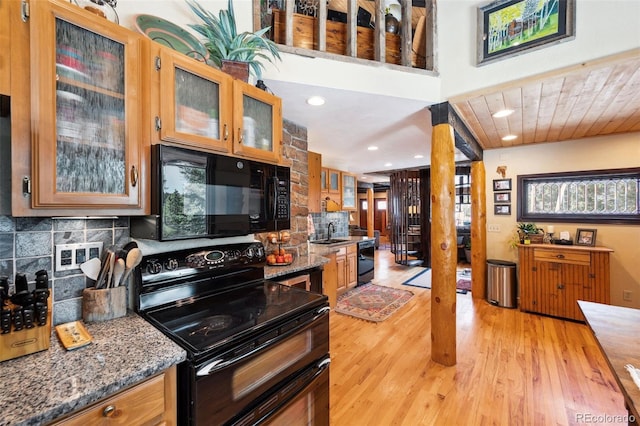 266 Lodgepole Dr, Evergreen, CO 80439 - kitchen with a sink, dark stone counters, brown cabinets, black appliances, and glass insert cabinets