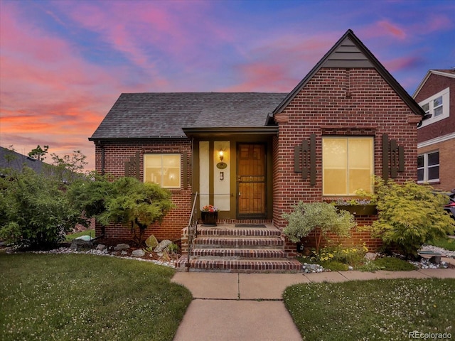 1247 Dexter St, Denver, CO 80220 - view of front of property featuring brick siding, roof with shingles, and a lawn