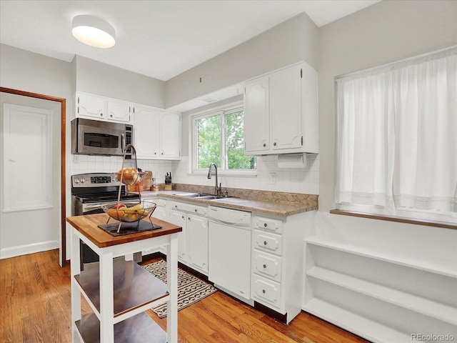 1247 Dexter St, Denver, CO 80220 - kitchen featuring appliances with stainless steel finishes, a sink, backsplash, and white cabinets