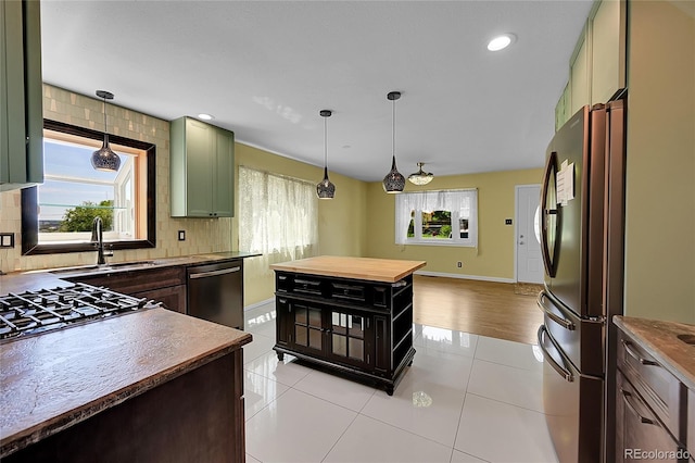 3145 S Bryant St, Sheridan, CO 80110 - kitchen featuring appliances with stainless steel finishes, green cabinetry, backsplash, light tile patterned flooring, and decorative light fixtures