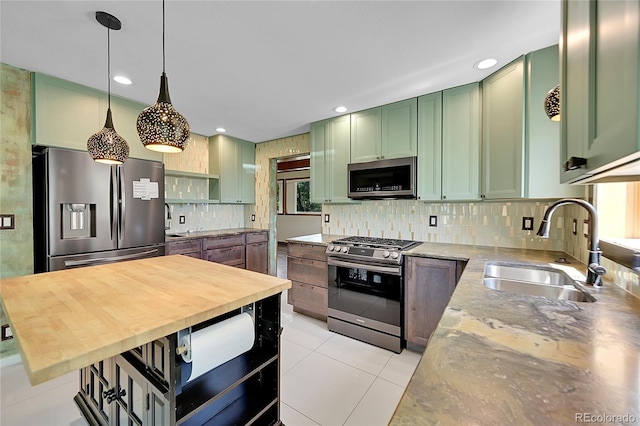 3145 S Bryant St, Sheridan, CO 80110 - kitchen with green cabinets, stainless steel appliances, decorative backsplash, hanging light fixtures, and light tile patterned floors