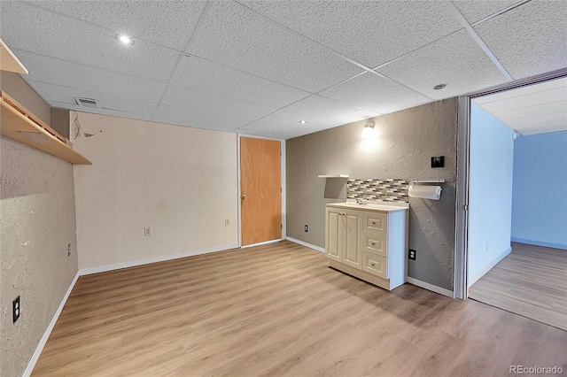 3145 S Bryant St, Sheridan, CO 80110 - unfurnished living room featuring light wood finished floors, a paneled ceiling, and a textured wall