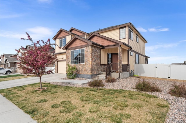 craftsman inspired home with fence, stone siding, board and batten siding, a gate, and driveway