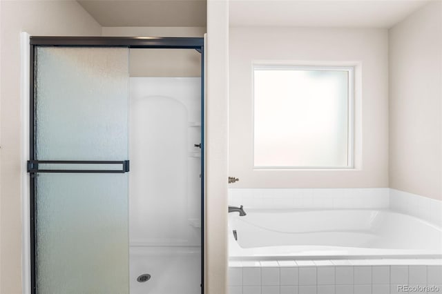 bathroom featuring a shower stall and a bath
