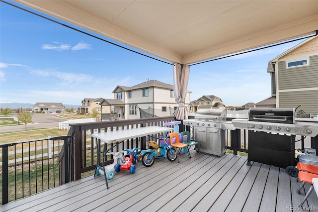 wooden deck featuring a lawn, a residential view, and a grill
