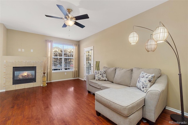 living room with wood-type flooring, a tile fireplace, and ceiling fan