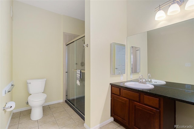 bathroom featuring toilet, vanity, tile patterned floors, and a shower with shower door