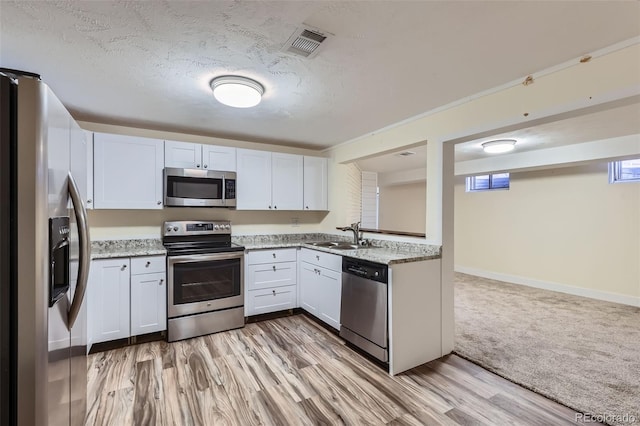 kitchen featuring visible vents, light wood-type flooring, a sink, a textured ceiling, and appliances with stainless steel finishes