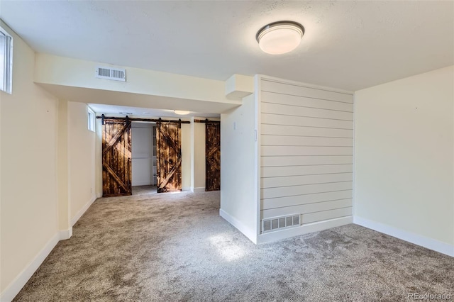 interior space featuring visible vents, a barn door, and baseboards