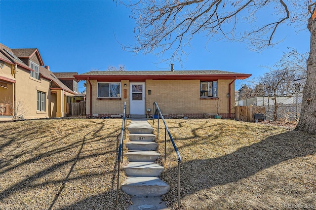 view of front facade featuring fence, brick siding, and crawl space