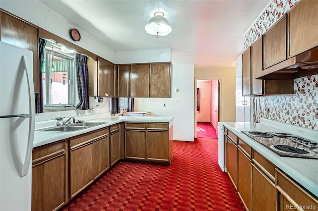 kitchen featuring under cabinet range hood, light countertops, freestanding refrigerator, electric stovetop, and a sink