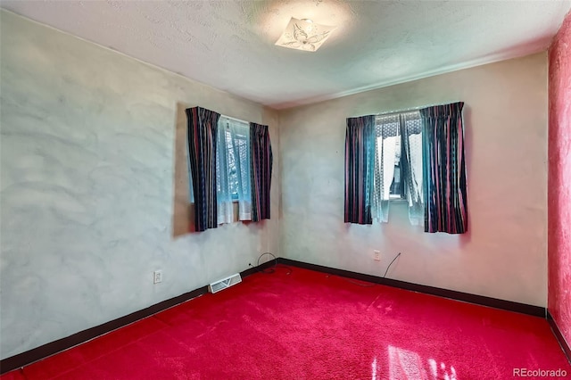 spare room featuring carpet flooring, a healthy amount of sunlight, visible vents, and baseboards