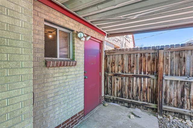 entrance to property with brick siding and fence