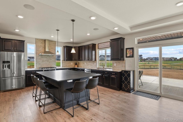 16002 E 111th Cir, Commerce City, CO 80022 - kitchen with stainless steel appliances, wall chimney exhaust hood, a kitchen breakfast bar, a sink, and light wood-type flooring