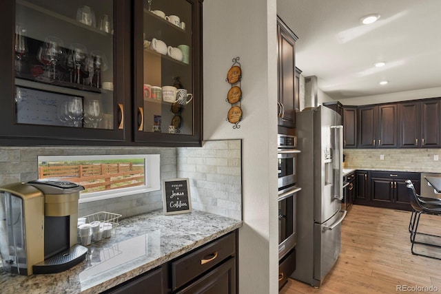 16002 E 111th Cir, Commerce City, CO 80022 - kitchen featuring decorative backsplash, dark brown cabinets, stainless steel fridge with ice dispenser, light wood-style flooring, and light stone counters