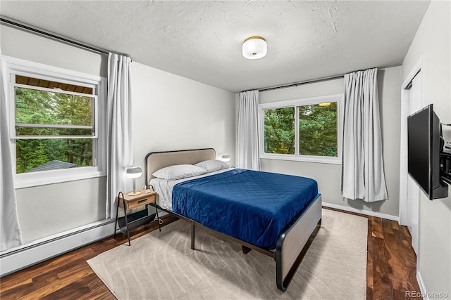6549 Modoc Ln, Evergreen, CO 80439 - bedroom featuring dark wood-style flooring, a textured ceiling, and a baseboard heating unit
