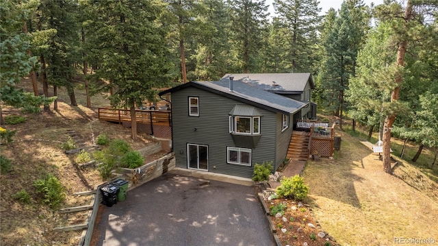 6549 Modoc Ln, Evergreen, CO 80439 - view of front of house with driveway, a deck, a patio, roof with shingles, and stairway