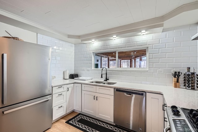 kitchen featuring a sink, stainless steel appliances, white cabinets, tasteful backsplash, and light wood-type flooring